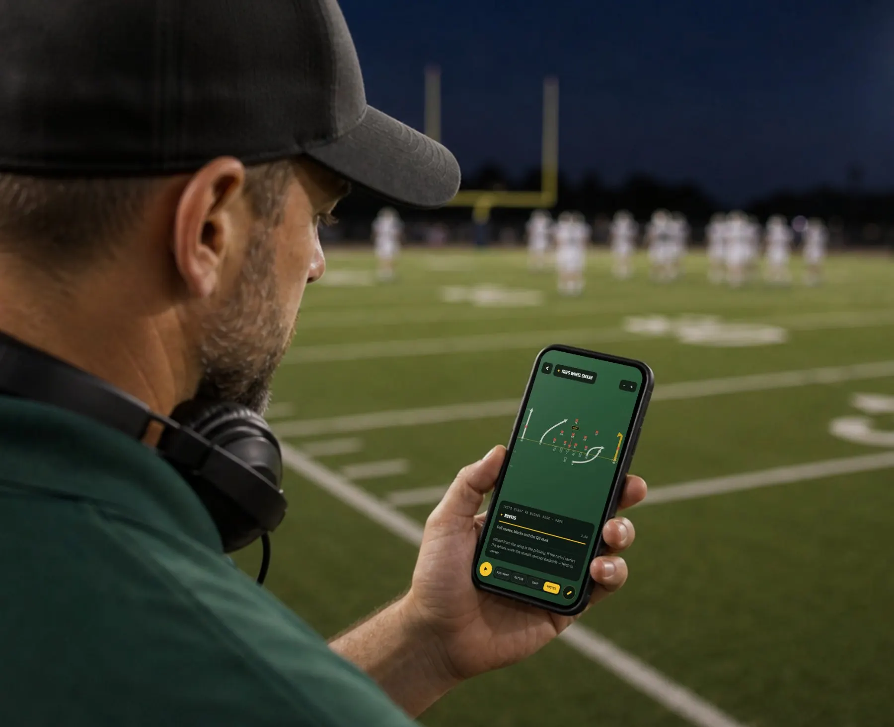 Coach on the sideline reading a play on his phone